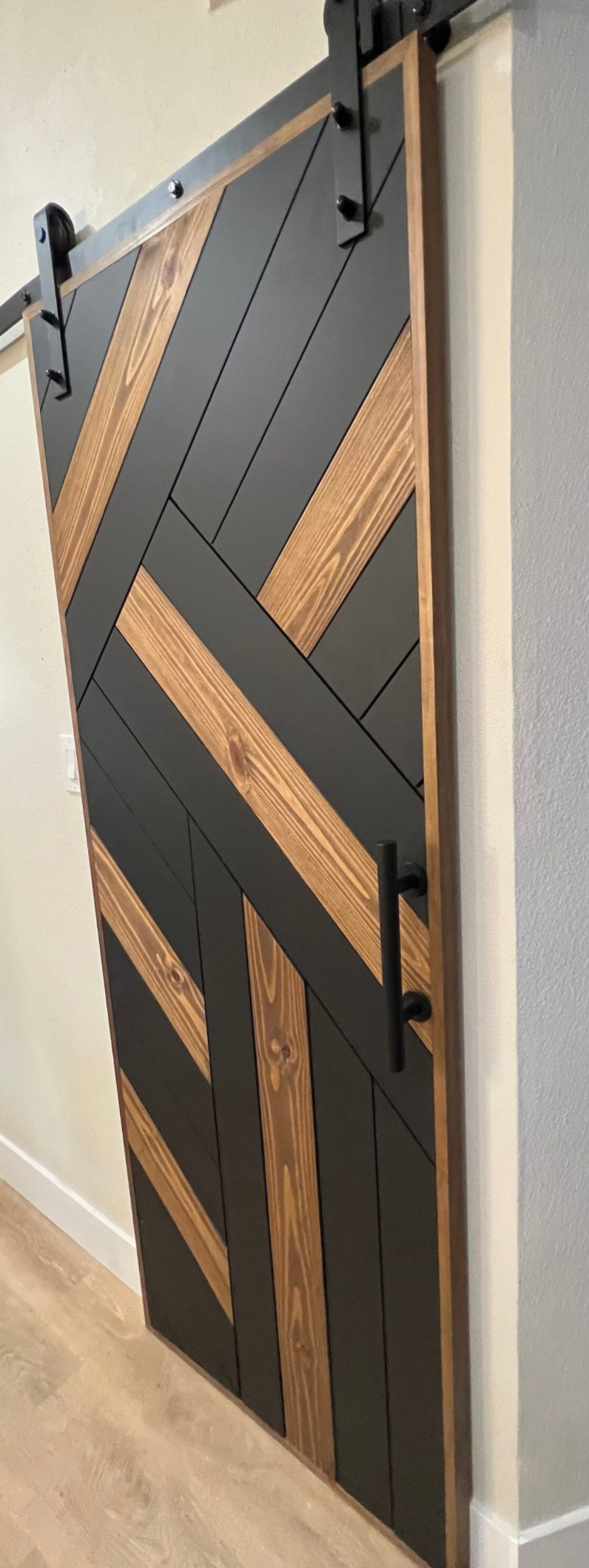 Custom modern white oak barn door with black geometric line inlays and matte finish installed on a silent-glide track system.
